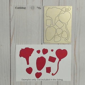May include: A clear Cuttlebug embossing folder and a gold Provo Craft die-cut template with heart and floral shapes are displayed. Below, red die-cut shapes of hearts and flowers are arranged on a white background. The text "Examples only- not included in the listing" is visible.