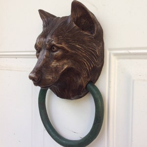 May include: A bronze wolf head door knocker with a green metal ring.