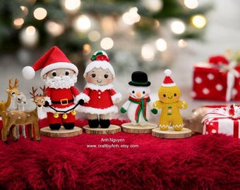 May include: A set of four crocheted Christmas ornaments: Santa Claus, Mrs. Claus, a snowman, and a gingerbread person. The ornaments are standing on wooden bases and are arranged in a row on a red fuzzy surface. The ornaments are all wearing traditional Christmas colors, such as red, green, and white.