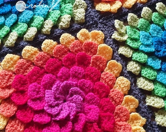 Könnte beinhalten: Nahaufnahme einer bunten Häkeldecke mit einem Regenbogenmuster. Die Decke besteht aus mehreren gehäkelten Blumen in verschiedenen Farben, darunter Rot, Orange, Gelb, Grün, Blau und Lila.