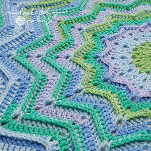 May include: Close-up of a crocheted blanket with a repeating pattern of stars in shades of blue, green, and purple.