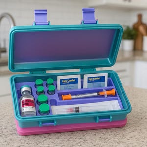 May include: An open, multi-colored medical kit with a teal top and base, a purple interior, and a pink bottom. The kit contains vials, syringes, and Easy Comfort packets. The kit is on a speckled countertop.