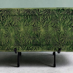 May include: A rectangular green ceramic serving tray featuring a raised, embossed floral pattern of coneflowers across the entire surface. The tray includes two integrated handles on the sides, each decorated with the same textured floral motif.