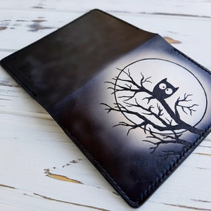 May include: Black leather wallet with a white owl design on a branch in front of a white moon.