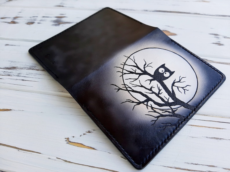 May include: Black leather wallet with a white owl design on a branch in front of a white moon.