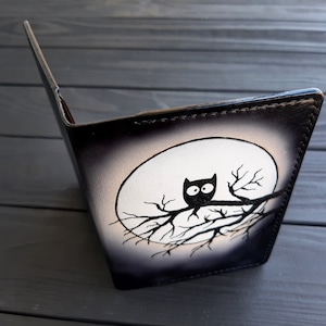 May include: Black leather notebook with a white moon and a black silhouette of an owl perched on a branch.