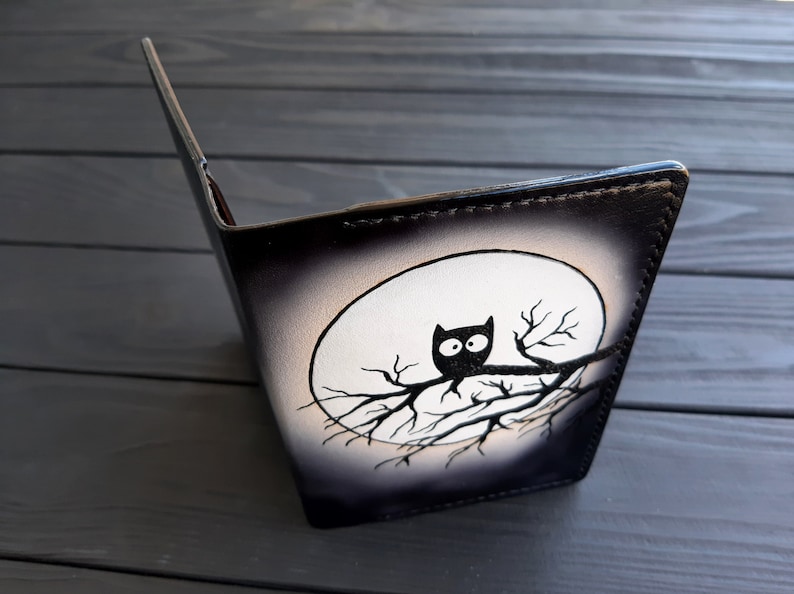 May include: Black leather notebook with a white moon and a black silhouette of an owl perched on a branch.