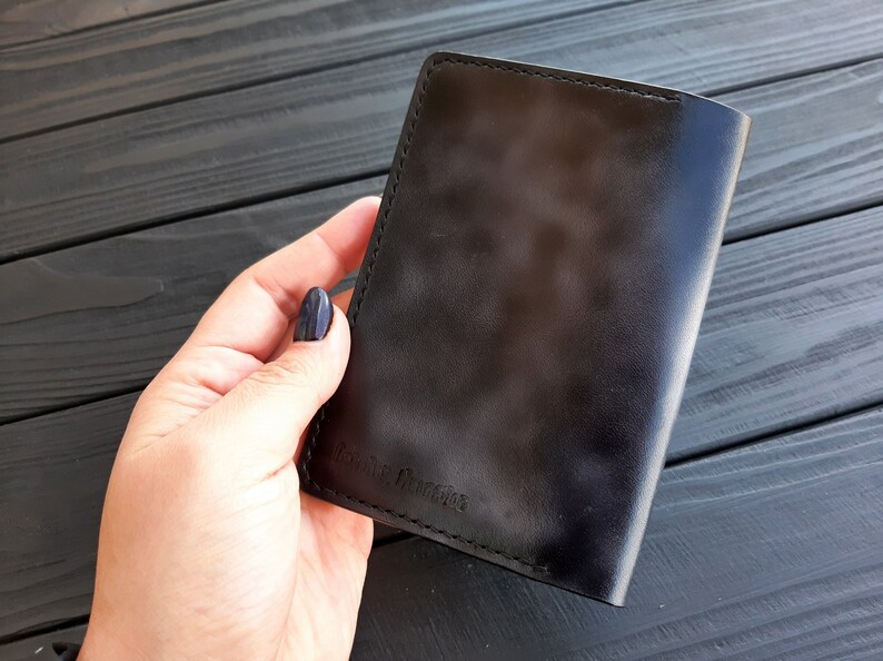 May include: A black leather passport holder with the text "Remarkable" embossed on the front.