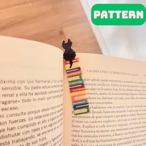 May include: A black cat bookmark made with colourful beads. The bookmark is a beaded pattern of a black cat sitting on a stack of books. The bookmark is about 15 cm tall.