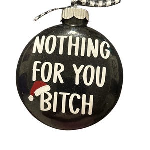 Puede incluir: Adorno navideño negro brillante con texto blanco "NOTHING FOR YOU BITCH". Incluye un pequeño gorro de Papá Noel. El adorno tiene una tapa plateada y una cinta a cuadros en blanco y negro para colgar.