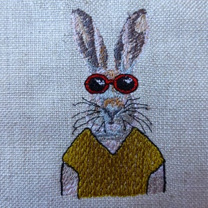 May include: Embroidered image of a rabbit wearing red sunglasses and a yellow shirt. The rabbit has brown and white fur and a long nose.