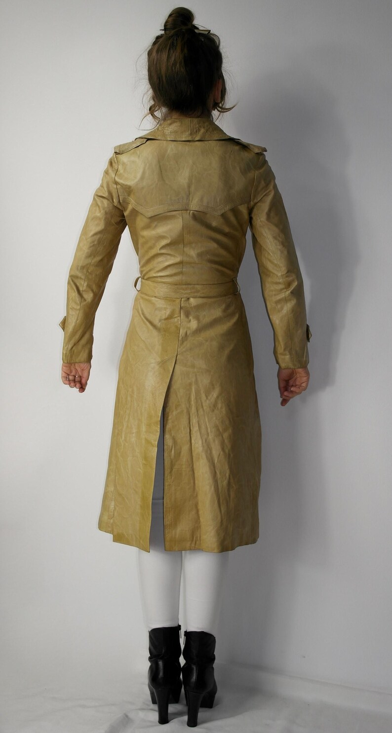 May include: A long, tan leather trench coat with a belt and a single back vent.