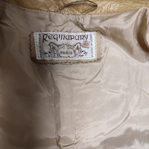 May include: A tan leather jacket with a brown leather label that reads "Regina Pary Paris Made in France 40".