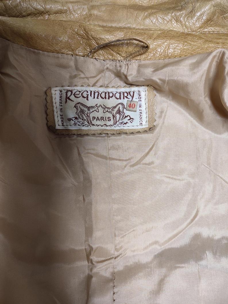 May include: A tan leather jacket with a brown leather label that reads "Regina Pary Paris Made in France 40".