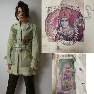 May include: A light green jacket with a frayed hem and a belt. The jacket has several patches sewn on, including one with a snake and the word "Essenza" and another with a woman in a green and red outfit and the words "Emerald Whip".