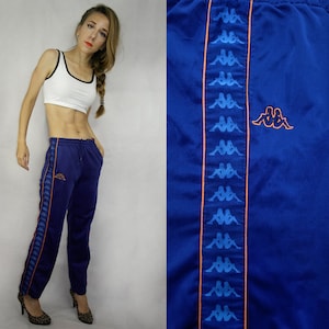 May include: Blue sweatpants with a white stripe down the side and a blue and orange Kappa logo on the left leg.