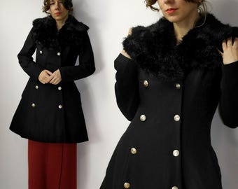 May include: A black double-breasted coat with a large black faux fur collar. The coat has a fitted bodice and a flared skirt.