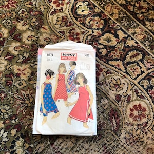 May include: A vintage sewing pattern for a dress and shorts. The pattern is for size 14, bust 34. The pattern is from le-roy Weldons and is number 8671. The pattern shows four different styles of dresses.