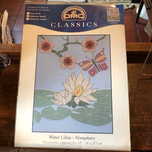 Puede incluir: Kit de punto de cruz contado DMC Classics con un diseño de nenúfares con una mariposa y flores rosas. El kit incluye instrucciones y materiales para crear una pieza terminada que mide 20 x 25,5 cm.