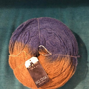 May include: A skein of brown and blue yarn with a label that reads "BIG DISK Made in Germany" and a smaller label that reads "Schoppel Wolle for you".