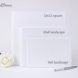 May include: Three white photo albums of different sizes. The largest album is 12x12 inches square, the middle album is 10x8 inches landscape, and the smallest album is 9x6 inches landscape.