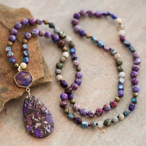 Peut inclure: Un long collier de perles violettes et dor&eacute;es avec un grand pendentif en pierre violette et dor&eacute;e.