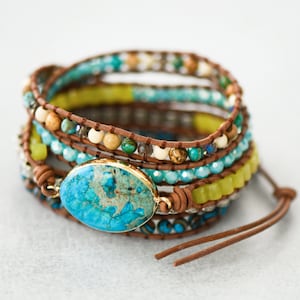 Peut inclure: Un bracelet enroulé multi-rangs avec un cordon en cuir marron et des perles turquoise, vertes et beige. Une grande pierre turquoise en cabochon est le point focal du bracelet.