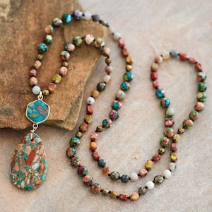 May include: A multi-strand necklace made of colorful, patterned beads with a teardrop-shaped pendant. The pendant is made of a light blue, brown, and white stone.