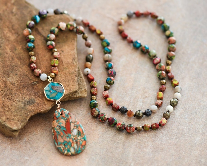 May include: A long multi-colored beaded necklace with a large turquoise and brown stone pendant. The necklace is made of various sizes and shapes of beads, including round, square, and hexagonal beads.