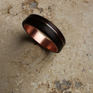 Op de afbeelding: Een donkerbruine houten ring met een koperen band rond de rand.