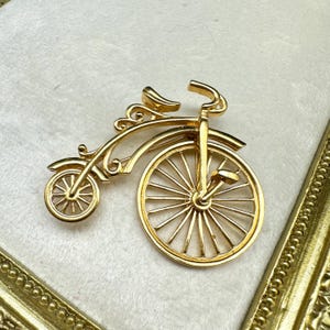 Vintage goudkleurige gelede driewieler, fietsbrochespeld in designerstijl