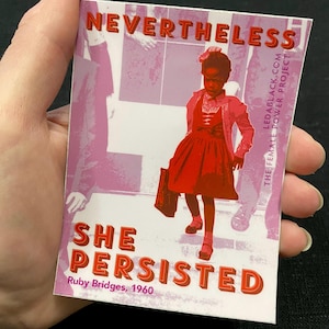May include: A rectangular sticker with the words "NEVERTHELESS SHE PERSISTED" in red and white lettering. The sticker features an illustration of Ruby Bridges, 1960, in a red dress and coat. The background is pink and white.