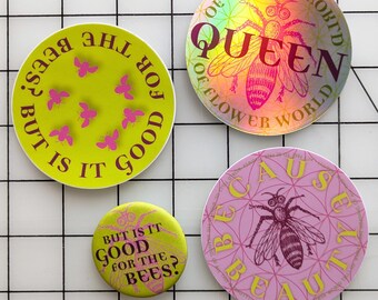 May include: Three circular stickers and one button pin. One yellow sticker reads BUT IS IT GOOD FOR THE BEES? with pink bee icons. A holographic sticker reads QUEEN OF FLOWER WORLD with a bee. A pink sticker reads BECAUSE BEAUTY with a bee. A yellow button pin reads BUT IS IT GOOD FOR THE BEES?