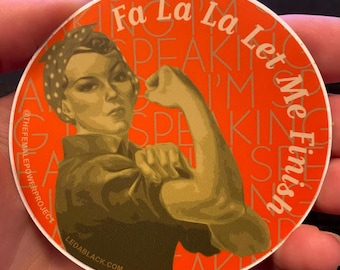 May include: A circular sticker with an orange background featuring a stylized illustration of a person flexing their arm. The text reads Fa La La Let Me Finish, THEFEMALEPOWERPROJECT, and LEDABLACK.COM in white and light orange lettering.