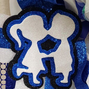 May include: A white glitter cutout of two people holding hands, outlined in black and blue glitter. The cutout is on a white background with blue glitter.
