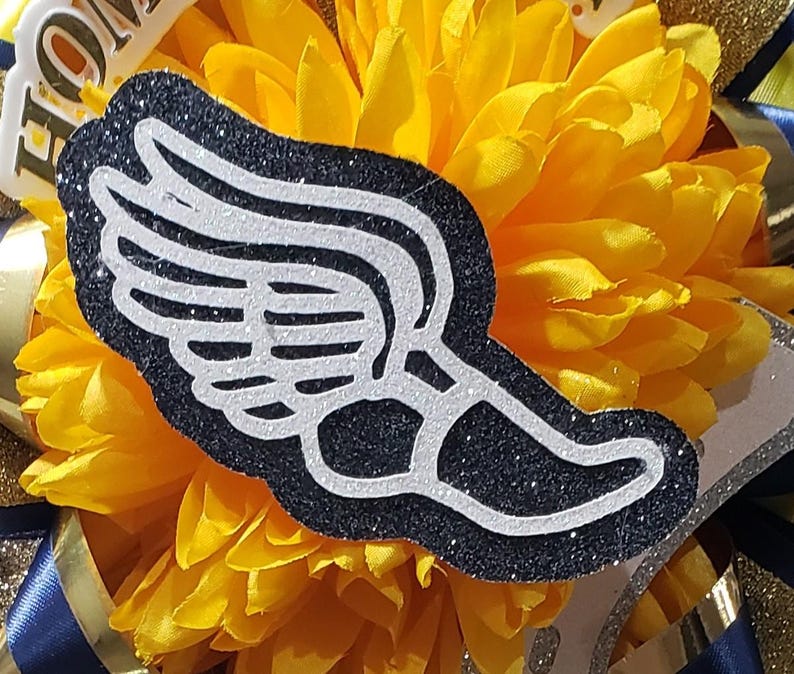 May include: A black and white glitter winged foot with a white outline. The foot is on a yellow flower.