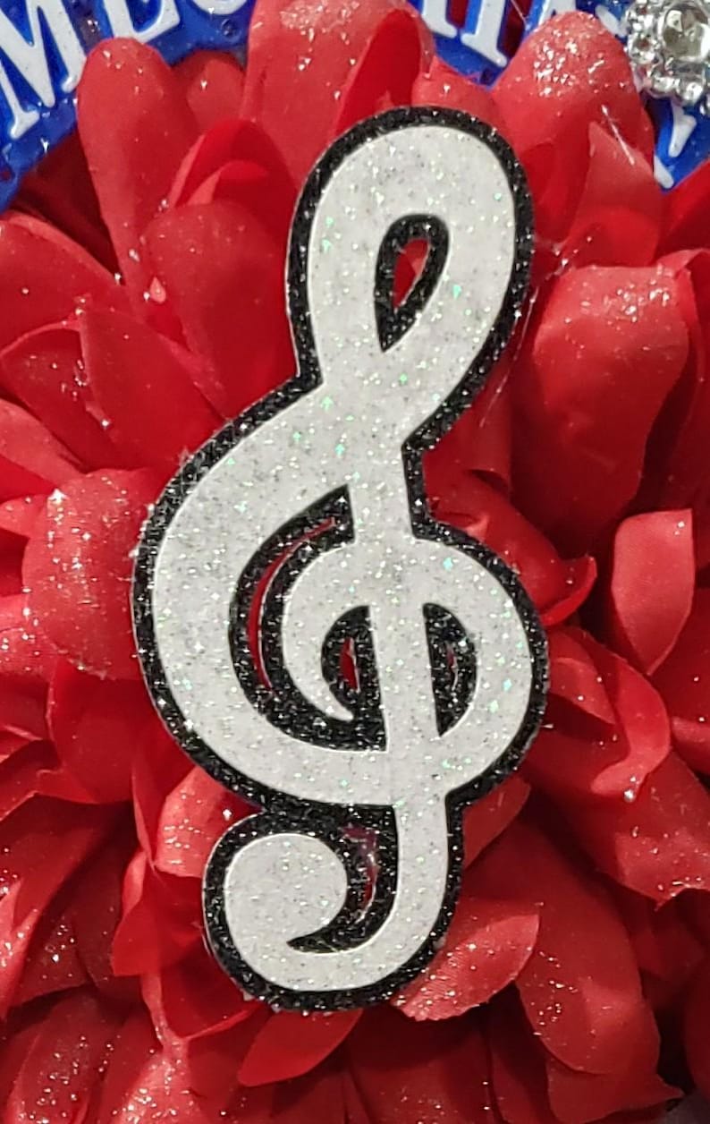 May include: A white glitter treble clef with a black outline on a red background.