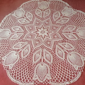 May include: A white crocheted doily with a delicate floral pattern. The doily is circular and has a scalloped edge.