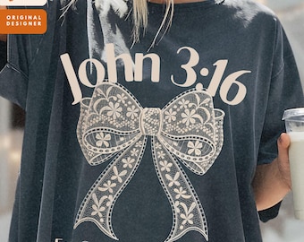 Könnte beinhalten: Dunkelgraues T-Shirt mit dem Text "John 3:16" über einer großen, detaillierten Schleife. Darunter steht der Text "For God so loved the world..." in einer Schriftart. Das T-Shirt hat eine lockere Passform.