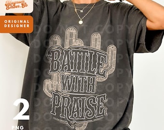 May include: A dark gray t-shirt with a graphic design of a cactus and the text "Battle with Praise".
