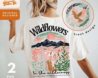 Op de afbeelding: Een wit T-shirt met een grafisch ontwerp op de achterkant. Het ontwerp toont een zonsondergang over bergen met wilde bloemen en de tekst "Wildflowers" en "In the wilderness I will make a way in the wilderness and rivers in the desert". De voorkant van het shirt heeft een klein grafisch ontwerp van een vogel in een cirkel met de tekst "front design".