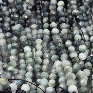 May include: A strand of faceted gray and black gemstone beads. The beads are round and have a smooth, polished finish.