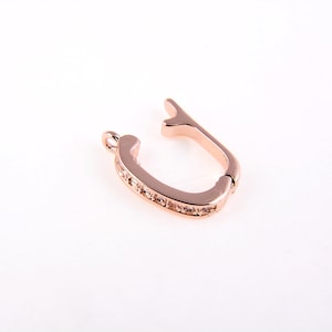 May include: Rose gold tone metal clasp with clear crystal accents. The clasp is designed to open and close securely.