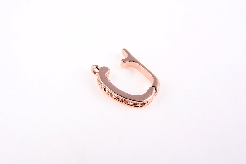 May include: Rose gold tone metal clasp with clear crystal accents. The clasp is designed to open and close securely.
