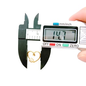 May include: A gold heart-shaped charm with a small cluster of clear rhinestones, measured at 14.7 mm using a digital caliper.