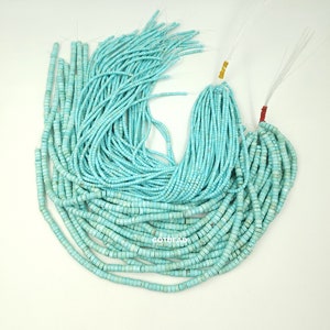 May include: A strand of turquoise blue beads, approximately 100 pieces, with a square shape and a smooth, polished finish. The beads are strung on a clear thread and are ready for jewelry making.