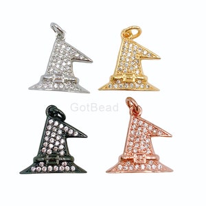 May include: Four witch hat charms in silver, gold, black, and rose gold. Each charm is encrusted with small, clear crystals. The charms have a loop at the top for attaching to jewelry. The witch hat charms are a Halloween theme.