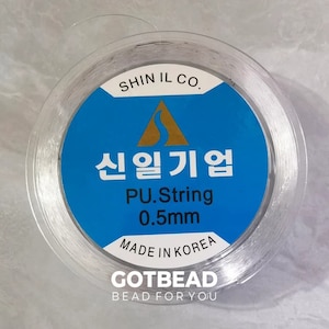 May include: A spool of clear elastic string for jewellery making. The label reads "SHIN IL CO. 신일기업 PU.String 0.5mm MADE IN KOREA GOTBEAD BEAD FOR YOU".