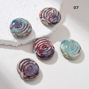 May include: Five ceramic beads with a spiral design in shades of blue, red, and white. The beads are oval-shaped and have a glossy finish. The number "07" is visible in the upper right corner.
