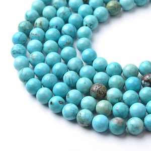 May include: A close-up of a strand of turquoise beads. The beads are a vibrant turquoise color with natural variations in tone and texture. Some beads have brown and gray matrix patterns. The beads are round and appear to be approximately 8mm in diameter.